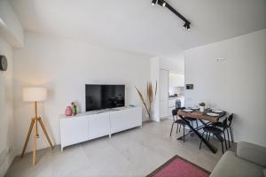 a white living room with a television and a table at Villa Almaris in Marina di Ragusa