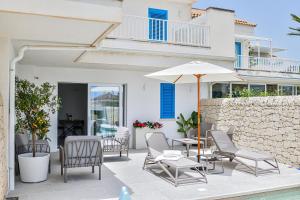 a patio with chairs and a table and an umbrella at Villa Almaris in Marina di Ragusa