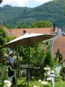 a woman sitting at a table under an umbrella at Les chambres noires in Mélisey