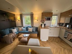 a living room with a blue couch and a kitchen at Het Strandnest in Renesse