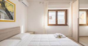 a white bedroom with a bed and a window at Dimoras 3BR City Center Terrace & Parking in Olbia