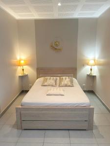 a bed in a room with two lamps on the wall at Residence D Été in Propriano