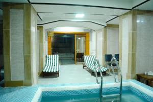 a swimming pool with two chairs and a tub at Taj Palace Hotel & Spa in Dushanbe
