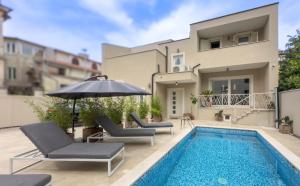 a swimming pool with two chairs and an umbrella next to a house at Villa Damiani " Partys and loud music forbidden!!!" in Pula