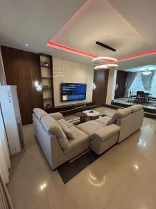 a living room with a couch and a tv at Omas Apartment in Abuja