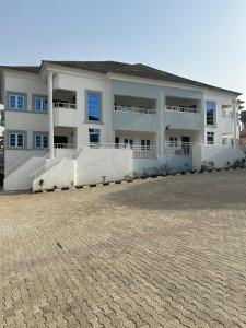a large white building with blue windows and a driveway at Omas Apartment in Abuja