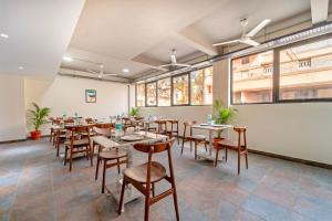 a dining room with tables and chairs and windows at Treebo Premium Cachet Suites in Coimbatore