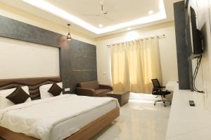 a bedroom with a bed and a couch and a television at Hotel Sunny Jhalawar in Jhālāwār