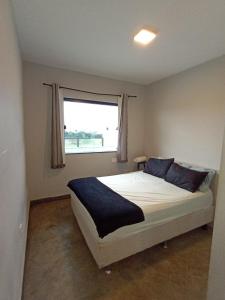 a bedroom with a large bed with a window at Edicula paixão in Muzambinho