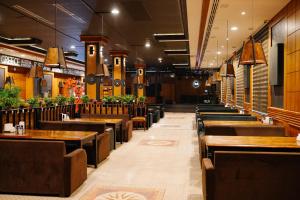 a restaurant with wooden tables and benches in a room at Taj Palace Hotel & Spa in Dushanbe