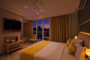 a bedroom with a bed and a window with a view at Phoenix Unmatched Comfort - Hotel Near Fateh Sagar Lake Udaipur in Udaipur