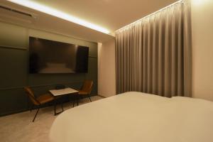 a bedroom with a bed and a table and a television at 잠실 라운지 호텔 in Seoul +48 photos