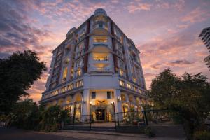 a tall white building with a sunset in the background at Phoenix Unmatched Comfort - Hotel Near Fateh Sagar Lake Udaipur in Udaipur