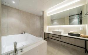 a bathroom with a tub and a large mirror at 잠실 라운지 호텔 in Seoul