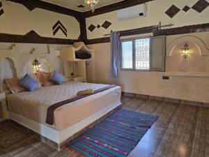 a bedroom with a large bed and a blue rug at Riad Berber Merzouga in Merzouga +32 photos