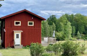 a red barn with a deck in a field at Three Bedroom Cottage Scenic Farm Views Lake Access and Free Boat in Valdemarsvik +23 photos