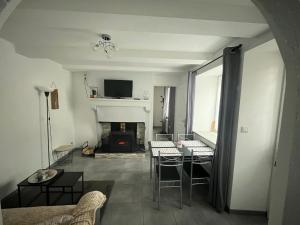 a living room with a fireplace and a table and chairs at Gîte au Petit Café in Châteauvillain