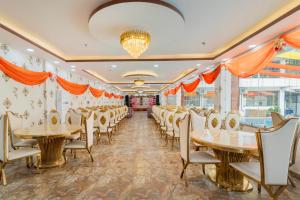a row of tables and chairs in a room with orange drapes at Treebo Arya Palace With Swimming Pool in Dehradun +38 photos