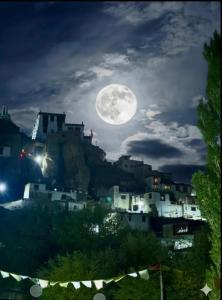a full moon over a city at night at ཨོཾ Homestay in Lāmayūrū