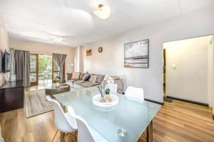 a living room with a glass table and white chairs at Tashy Luxury 2 bedroomed apartment in Johannesburg