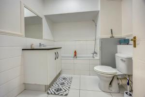 a white bathroom with a toilet and a bath tub at Tashy Luxury 2 bedroomed apartment in Johannesburg