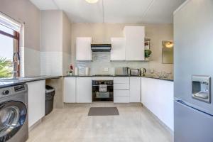 a kitchen with white cabinets and a washer and dryer at Tashy Luxury 2 bedroomed apartment in Johannesburg +4 photos