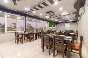 a restaurant with wooden tables and chairs and windows at Treebo Arya Palace With Swimming Pool in Dehradun