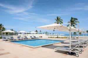 a pool with chairs and umbrellas and the ocean at Diamonds Bijoux in Bwejuu