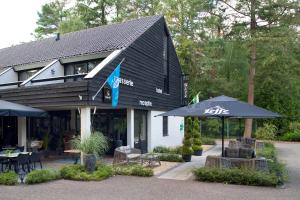 a restaurant with umbrellas in front of a building at Lodge met eigen wellness onder de bomen in Lochem