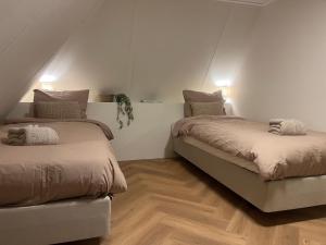 two beds in a room with white walls and wood floors at Lodge met eigen wellness onder de bomen in Lochem