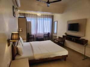 a hotel room with a bed and a television at Vagator Beachside Apartment with Pool by Welkin Stays in Vagator