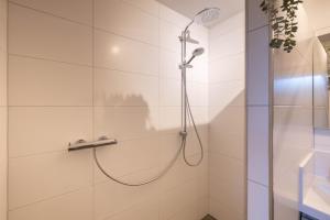 a shower with a shower head in a bathroom at Lodge met eigen wellness onder de bomen in Lochem +38 photos