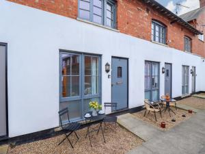 a white building with chairs and a table on a patio at 3 The Old Drill Hall in Alford
