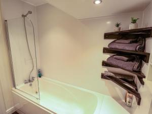 a bathroom with a shower and some towels and a tub at 3 The Old Drill Hall in Alford +14 photos