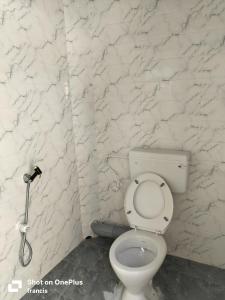 a bathroom with a toilet and a white marble wall at Johan home stay AC in Thiruchendur