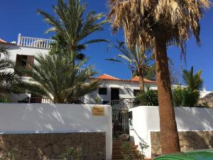 a white house with palm trees in front of it at Las Americas Family Inn in Playa de las Americas