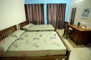 two beds in a room with a desk and a desk at Devaki Tourist Home in Ambalapulai
