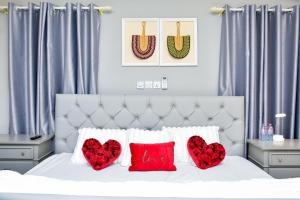 a white bed with two red pillows and two hearts at THE AFRICAN PALACE- Free Airport Pick up - High Speed Starlink WiFi - Car Rental in Tamale