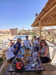 a group of people sitting around a table with food at Riad Berber Merzouga in Merzouga