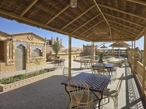 an outdoor patio with tables and chairs and umbrellas at Riad Berber Merzouga in Merzouga