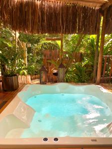 a jacuzzi tub sitting under a straw umbrella at Bangalô Maria, luxo próximo ao mar in Trancoso
