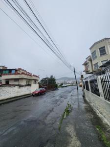 an empty street with a red car parked on the road at Rincón del Descanso in Loja
