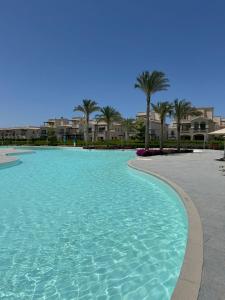 a large pool of water with palm trees and houses at Marassi villa in El Alamein