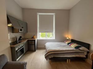 a bedroom with a bed and a kitchen with a window at Drumcondra Studio Apartment in Dublin