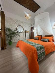 a bedroom with a large bed with an orange bedspread at Rahayu House in Kusamba