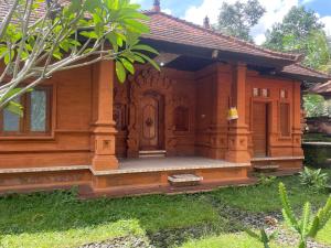 a wooden house with a porch in the yard at Rahayu House in Kusamba