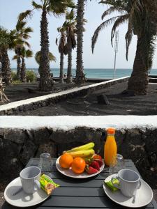 a table with two plates of fruit and drinks on it at CASA MACA sea view & beach front in Puerto del Carmen