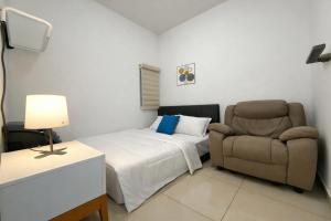 a bedroom with a bed and a couch and a chair at Alayam Villa Padalarang near whoosh, wahoo waterworld & ikea in Padalarang