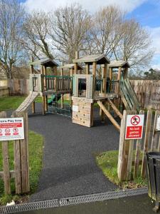 a wooden playground in a park with a fence at Quality City Hotel Restaurant Free Parking in Upton Warren