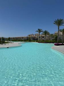 a large pool of water with palm trees and condos at Marassi villa in El Alamein